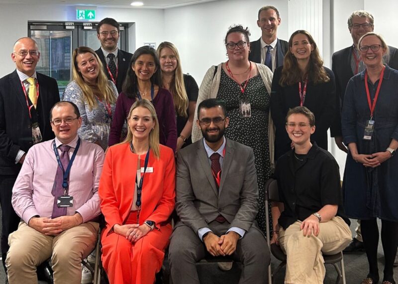 A group of professionals in business attire smiling and posing together for a formal photograph.