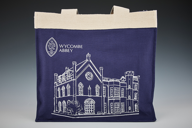 A navy tote bag with the Wycombe Abbey logo and an outline of the abbey in white.