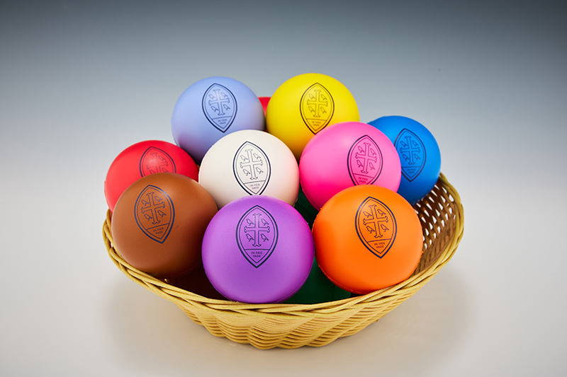 Different coloured stress balls, each with a Wycombe Abbey logo, in a wicker basket.