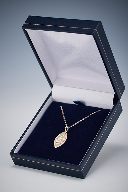 Silver Wycombe Abbey logo necklace in a navy box.